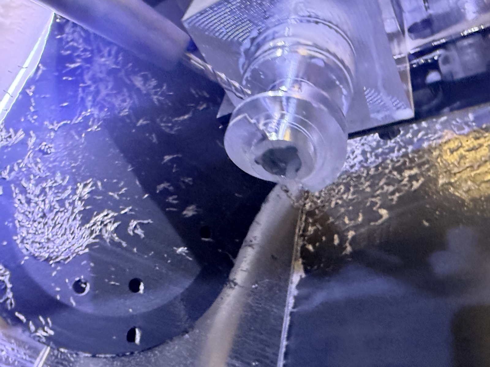 End mill cutting the inducer geometry, with chips and coolant across the machine table
