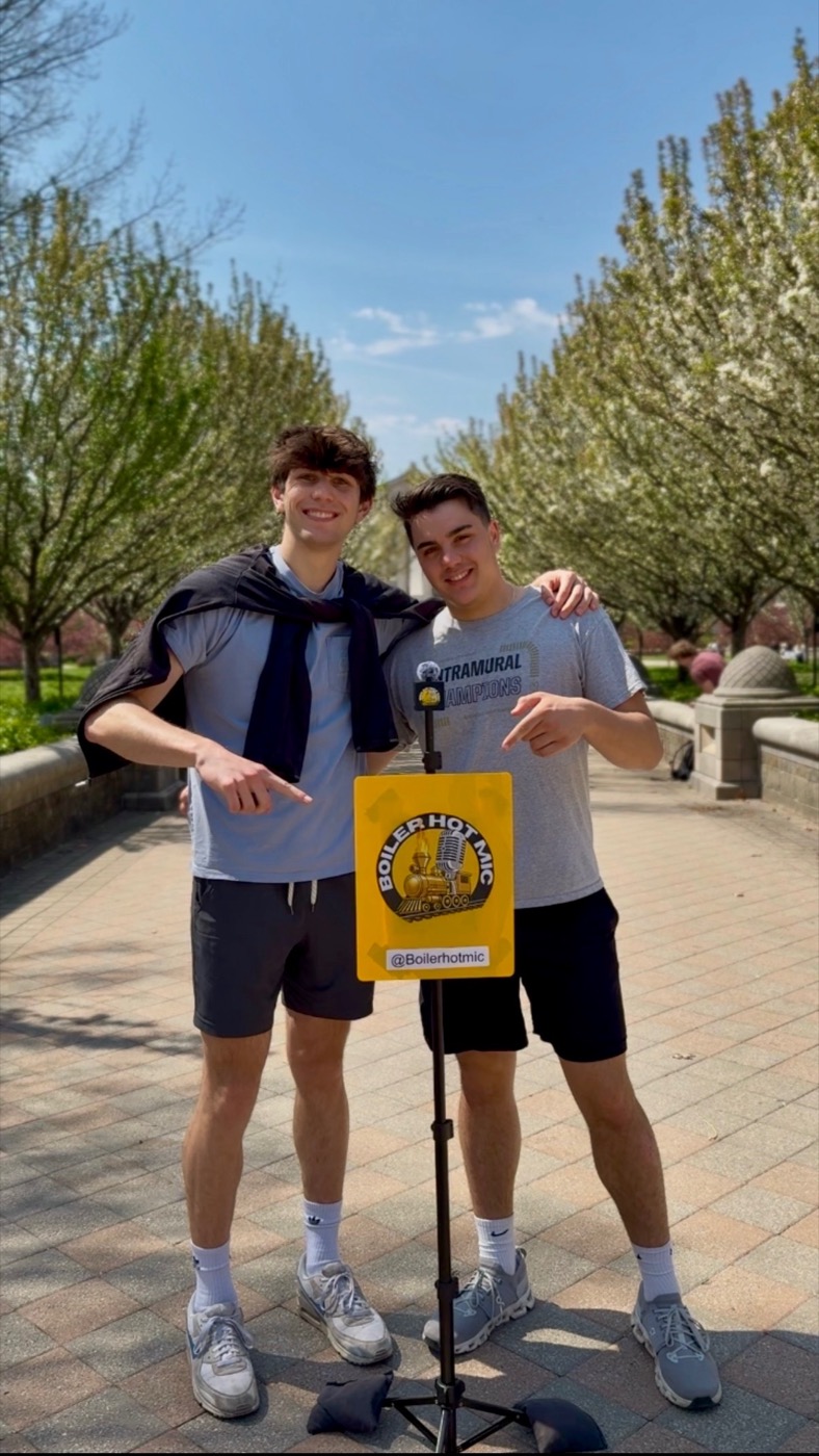 Ethan and his co-founder Jordan on the Purdue campus with the Boiler Hot Mic microphone and sign